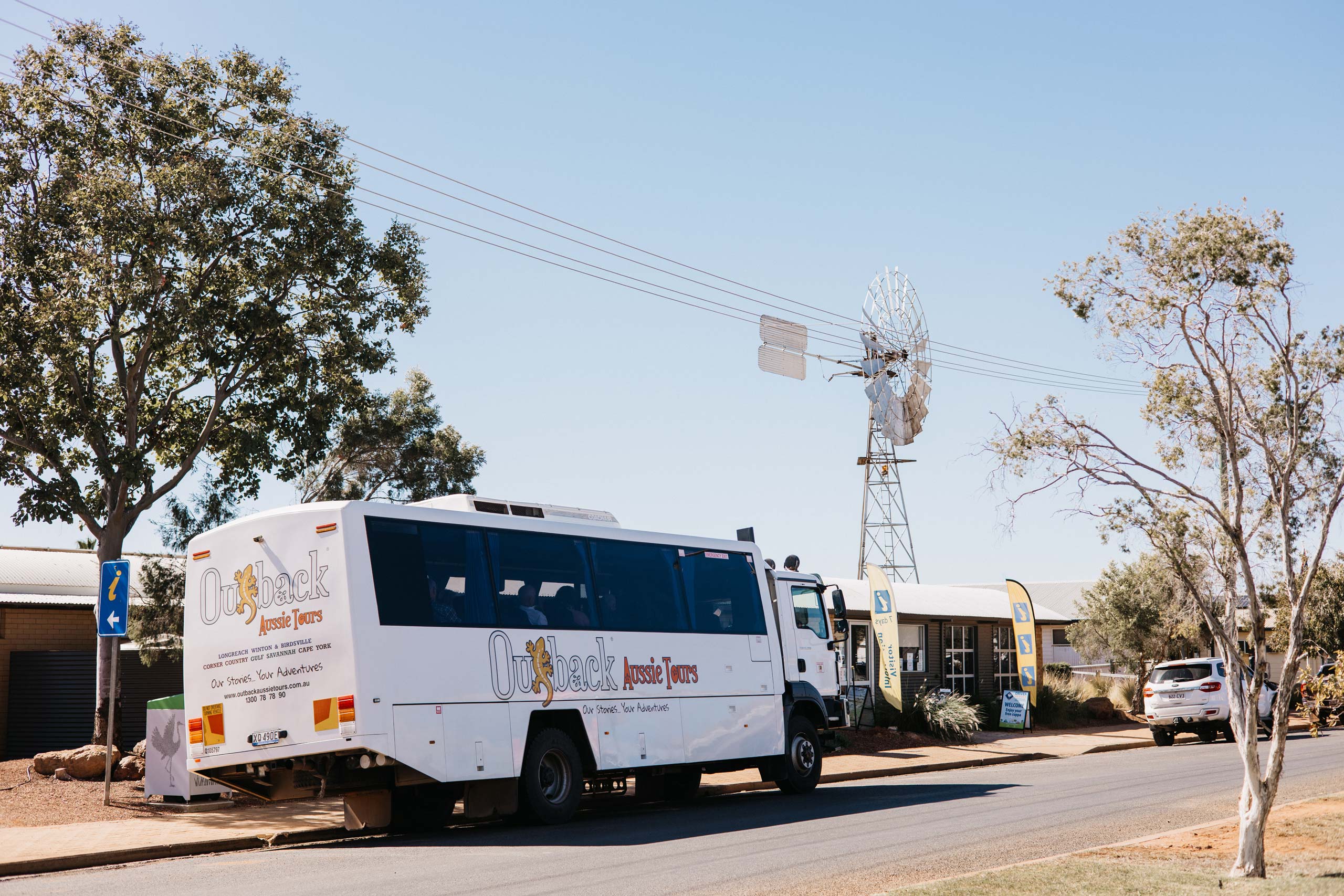 white tour bus parked outside of visitor information centre with silver windmill in the background